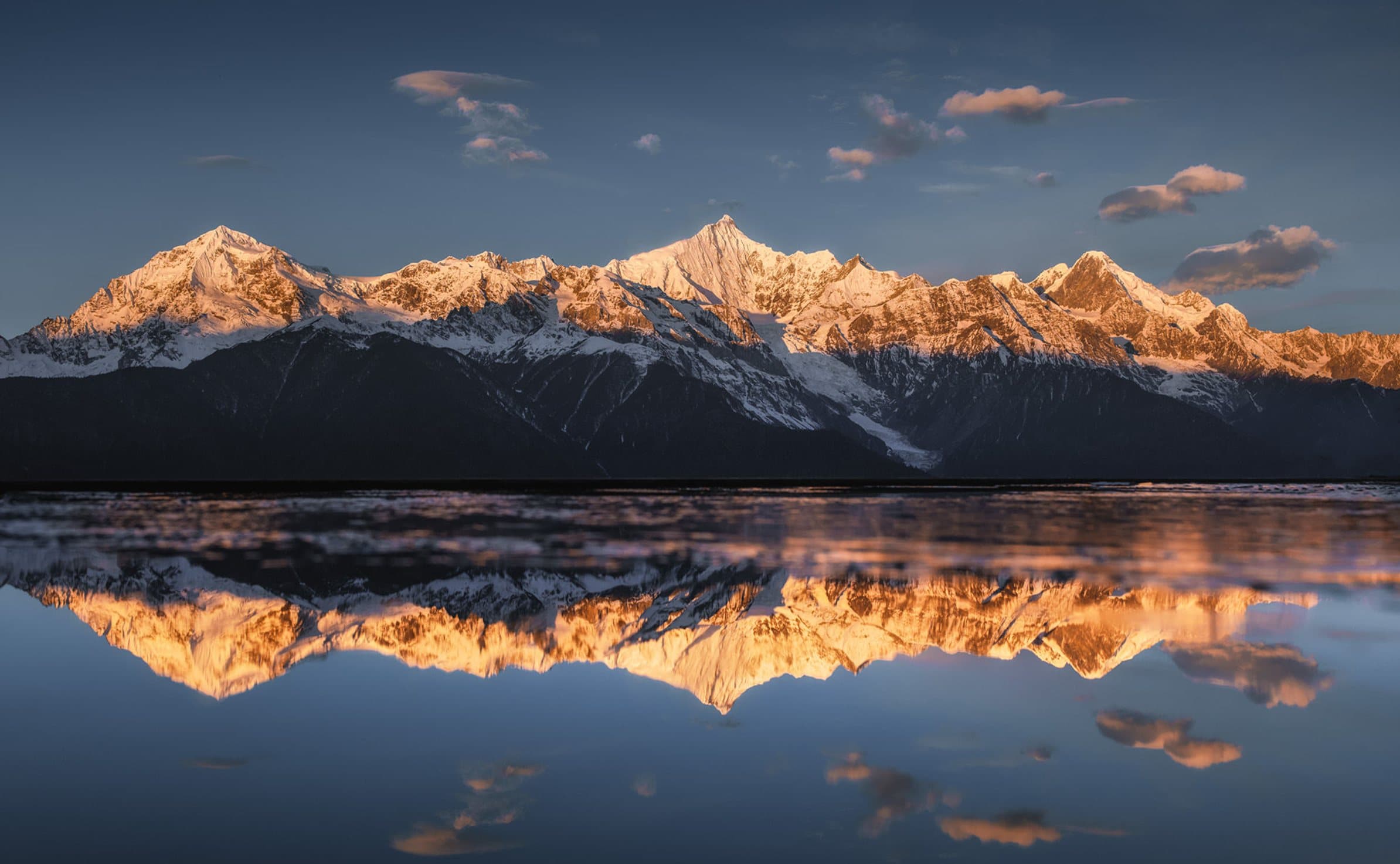 Snow peaks and reflections lit by morning sunlight