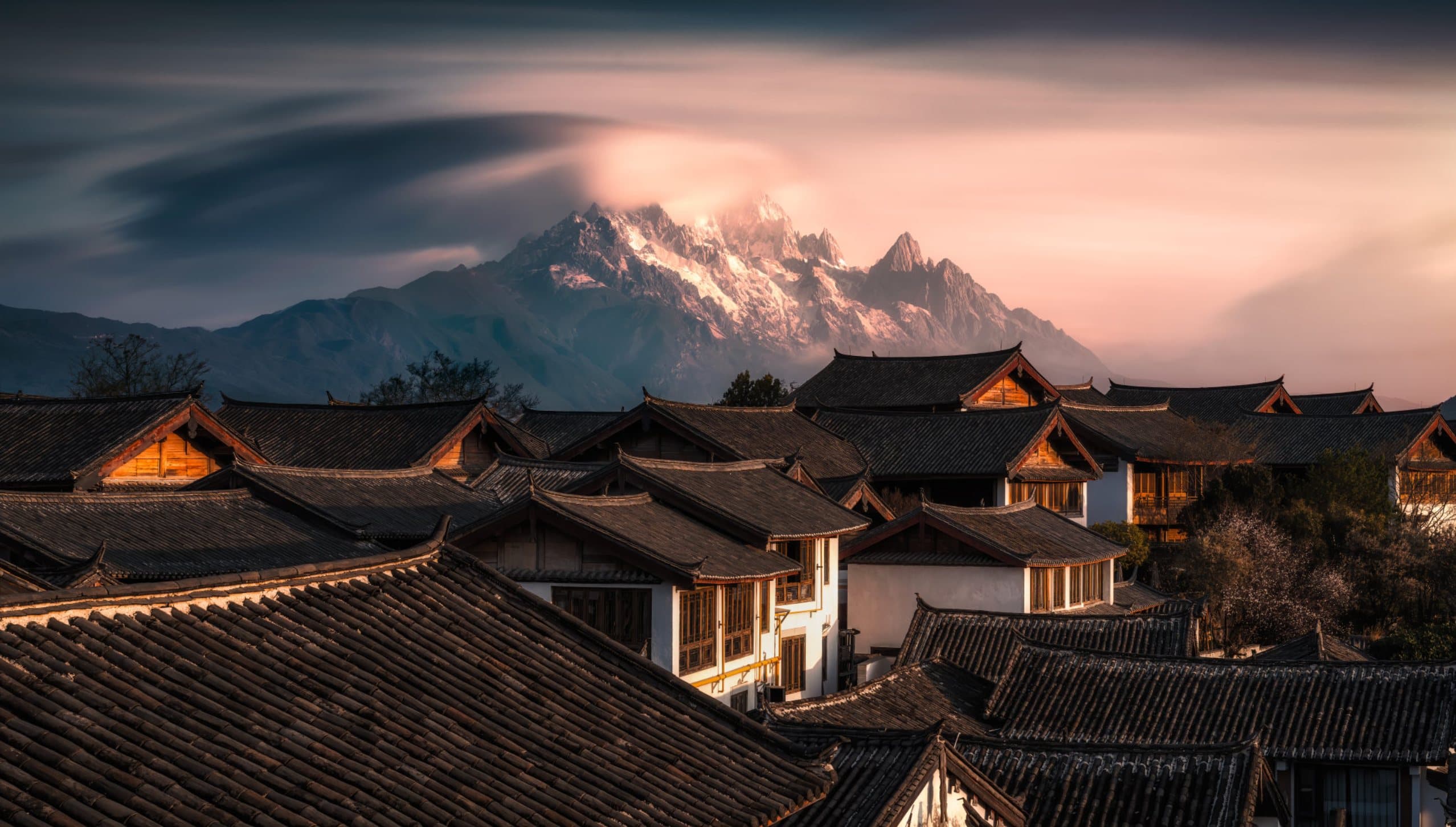 Tiled rooftops beneath distant snow peaks at dusk